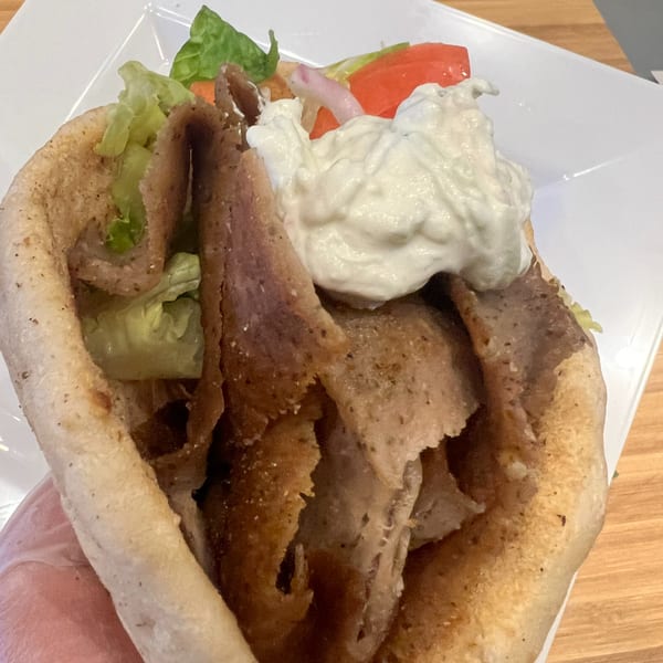 A Kalamaki Greek gyro with meat, lettuce, tomatoes, onions, and tzatziki sauce in pita bread.