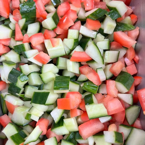 Close-up of diced cucumbers and tomatoes, ready for a fresh Greek salad.