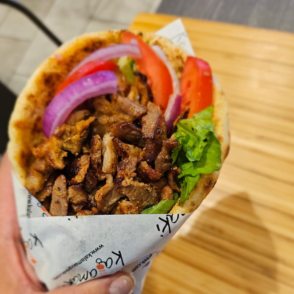 A Kalamaki Greek gyro with meat, red onions, tomatoes, and lettuce in pita bread.