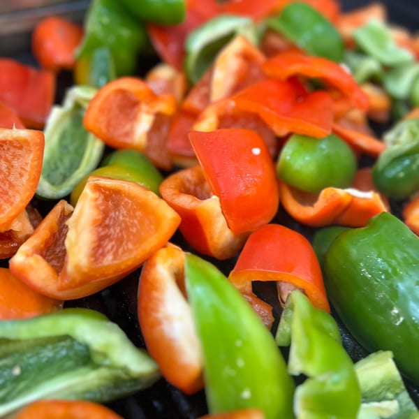 Chopped red and green bell peppers, ready for cooking, likely for a Greek dish at Kalamaki.
